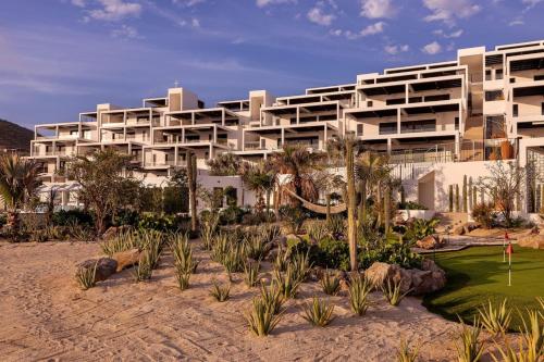 a large white building with palm trees in front of it at Boutique Ocean Escape with Relaxing Amenities in El Pescadero
