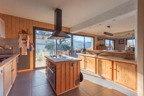 une grande cuisine avec des placards en bois et une grande fenêtre dans l'établissement Villa sur la colline aux Pyrénées, à Bagnères-de-Bigorre
