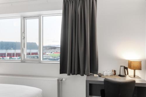 a bedroom with a bed and a desk with a window at Hotel Vellir in Hafnarfjördur