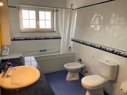 a bathroom with a toilet and a sink and a tub at FreeSurfCamp & Hostel in Peniche