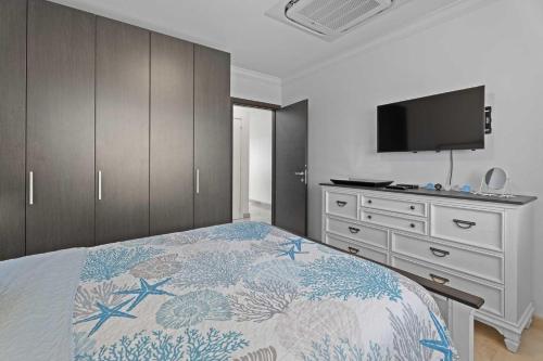 Un dormitorio con una cama y una cómoda con televisión. en PC412 - Pool View - 1BR Perfect for a couple or Family - Close to Palm Beach - 1BR, en Palm-Eagle Beach