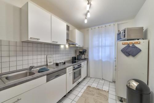 Una cocina blanca con fregadero y refrigerador. en Maisonette Duplex-Fewo Mathilde, en Bad Kreuznach