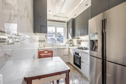 une cuisine avec un réfrigérateur en acier inoxydable et une table dans l'établissement GuestReady - Charming Stay near Museum of Illusion, à Paris