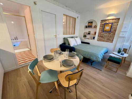 Ce petit appartement comprend une table, des chaises et un lit. dans l'établissement Le Bellegarde - hypercentre et jacuzzi, à Toulouse