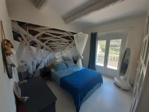 une chambre avec un lit bleu et une fenêtre dans l'établissement Au pied du Luberon, à Les Taillades