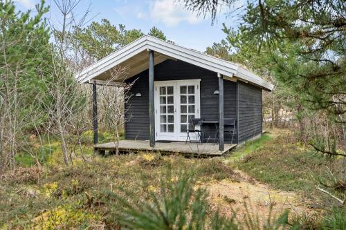 a small cabin with a porch in the woods at Charmerende skovhytte in Ringkøbing