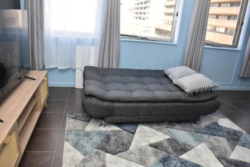 a couch sitting in a living room with windows at 305 Urban Oasis in Jozi CBD in Johannesburg