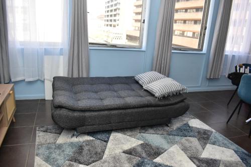 a couch sitting in a living room with windows at 305 Urban Oasis in Jozi CBD in Johannesburg