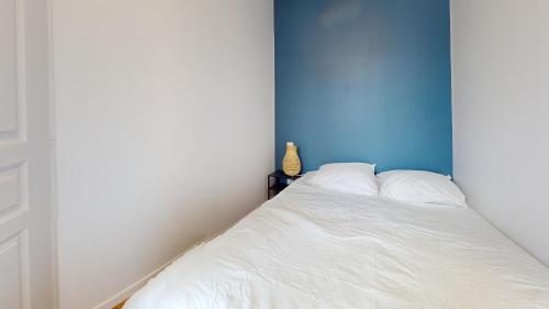une chambre avec un lit blanc avec un mur bleu dans l'établissement F1 bis - Garibaldi, au Havre