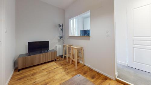 Cette chambre blanche dispose d'une télévision, d'une table et d'une porte. dans l'établissement F1 bis - Garibaldi, au Havre