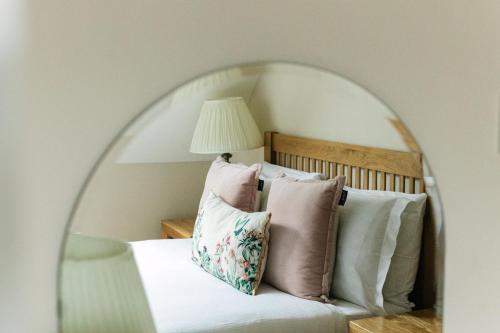 a bedroom with a bed with pillows and a mirror at Cotteswold House in Bibury