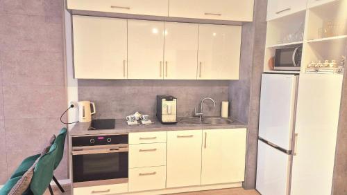 a kitchen with white cabinets and a white refrigerator at Apartament Szmaragdowe Love in Kołobrzeg