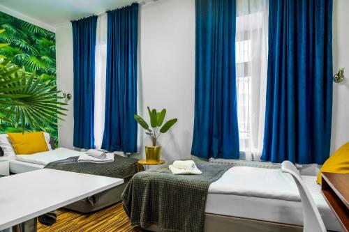 a bedroom with two beds and blue curtains at Great Polonia Dwarf Wrocław in Wrocław