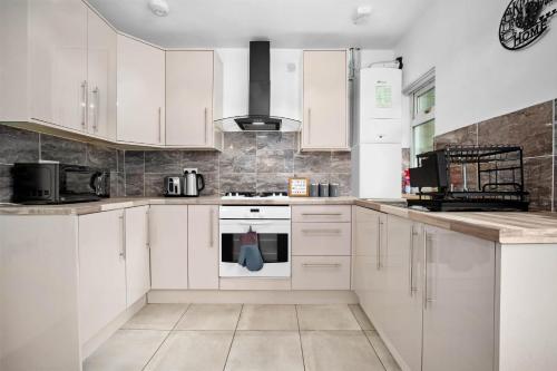 a kitchen with white cabinets and a stove top oven at House In Erdington in Birmingham