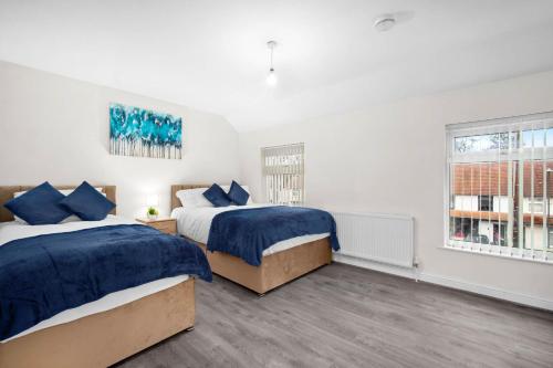 two beds in a room with two windows at House In Erdington in Birmingham
