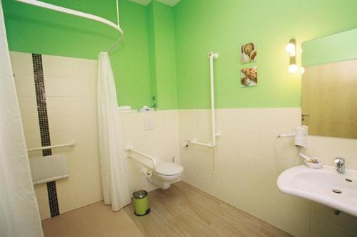 a green and white bathroom with a toilet and a sink at Hotel zur Insel in Werder