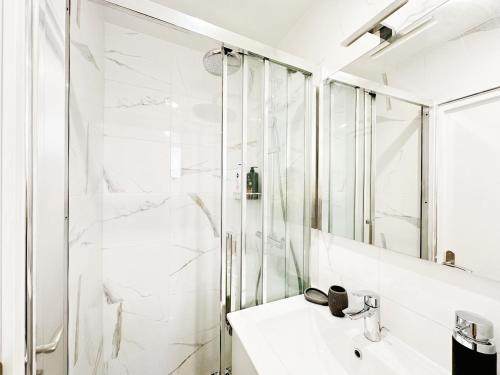 une salle de bain blanche avec une douche et un lavabo dans l'établissement Apt lumileux with sunshine, à Paris