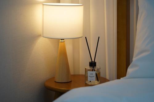 a lamp sitting on a table next to a bed at Busan Subway 6min #2 Rooms #2 Queen Beds #Hotel Bedding #OTT #Table#1st Floor in Busan