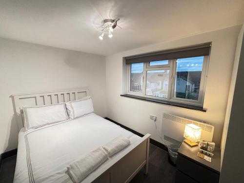 a bedroom with a white bed and a window at Southall Edge Inn in Southall
