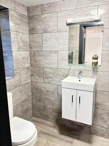 a bathroom with a toilet and a sink and a mirror at Southall Edge Inn in Southall