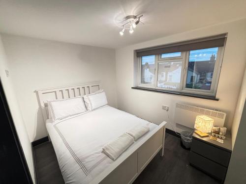 a bedroom with a white bed with a window at Southall Edge Inn in Southall