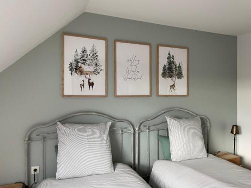 2 posti letto in una camera da letto con 3 immagini sul muro di Un air de campagne a Châtenois