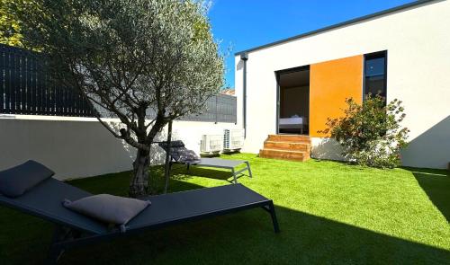a garden with a tree and a bench and a building at DAYA LODGE. in LʼIsle-sur-la-Sorgue
