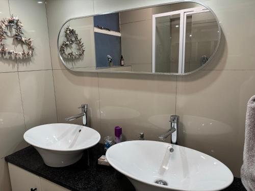 a bathroom with a white sink and a mirror at Stadium Apartment in Cape Town