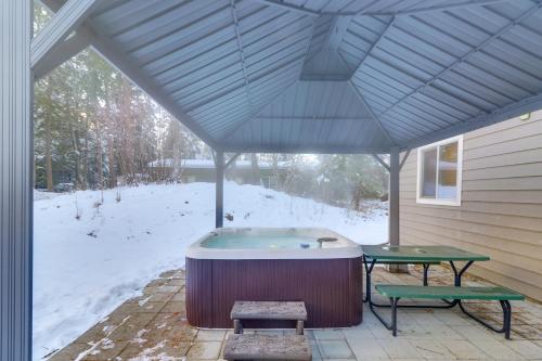 a hot tub on a patio with two picnic tables at Columbia Falls Private Retreat Pool Table and Deck! in Columbia Falls