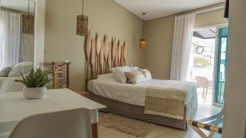 a bedroom with a bed and a table and a window at Hotel VillaReal Charme in Guaratuba