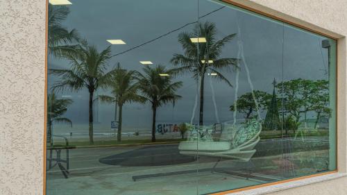 a glass window with a chair and palm trees at Hotel VillaReal Charme in Guaratuba