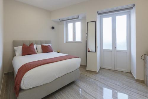 a bedroom with a bed with white sheets and red pillows at Solar Mendonca in Faro