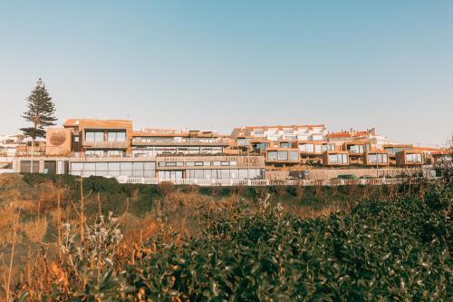 a group of buildings on a hill with trees at Noah Surf House Portugal in Santa Cruz