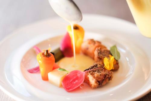 a white plate with food on a table at Hotel Ristorante Al Caminetto WorldHotels Crafted Adults Only in Torri del Benaco