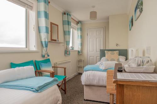 a bedroom with two beds and a desk and a table at Trevarrian Lodge in Newquay