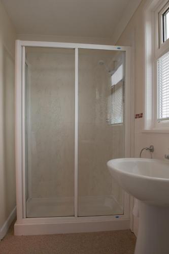 a shower with a glass door next to a sink at Trevarrian Lodge in Newquay