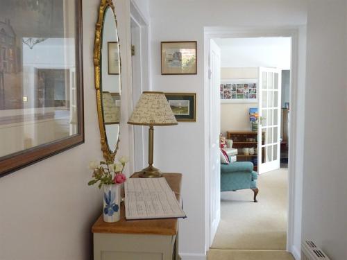 a hallway with a table with a lamp and a mirror at Honey Lodge in Broadstone
