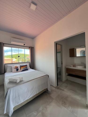 a bedroom with a bed with a window and a sink at Suítes Preguiça in Sao Jorge