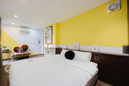 a bedroom with a large bed and a yellow wall at Rik Homestay in Hanoi
