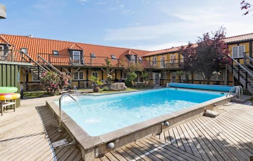 a large swimming pool in a yard with buildings at Awesome Apartment In Svaneke With Wifi in Svaneke
