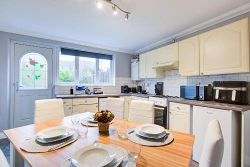 a kitchen with a wooden table and white cabinets at Clarence Cottage in Fleet