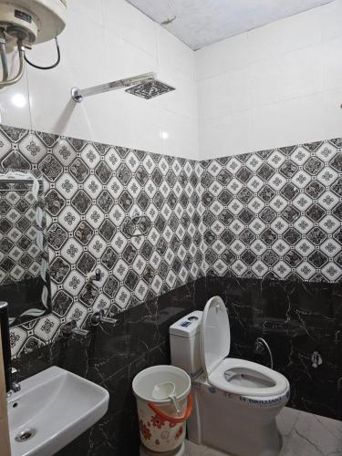 a black and white bathroom with a toilet and a sink at The Ashok Vatika Farms and Stay in Haridwār