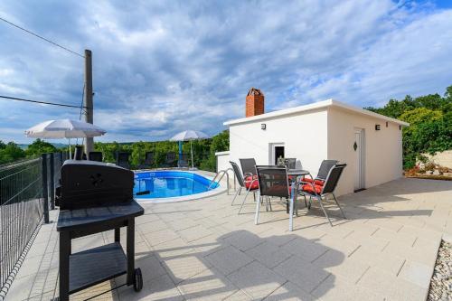 een terras met een tafel en stoelen en een zwembad bij Apartment Lara with Swimming Pool - Paradiz in Veli Turini