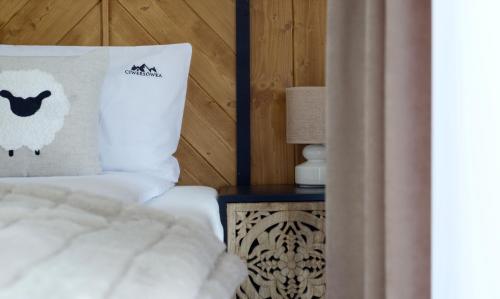 a bed with a pillow with a sheep on it at Ciwersówka Domki Białka Tatrzańska in Białka Tatrzanska