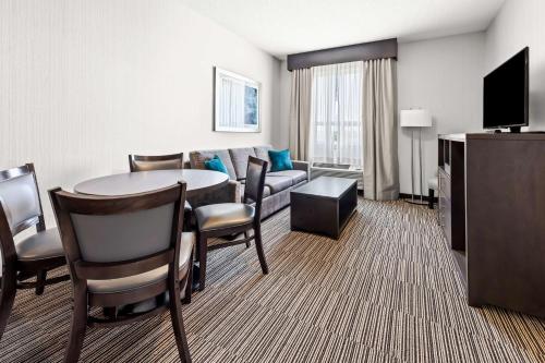 a hotel room with a table and a couch at Best Western Plus Airdrie Gateway in Airdrie