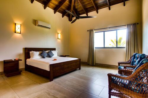 a bedroom with a bed and a chair at Naïa Resort and Spa in Placencia Village