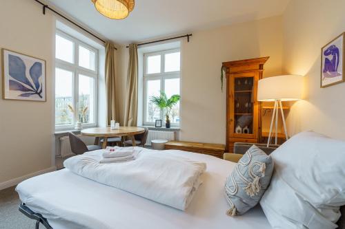 a bedroom with a bed and a table and windows at Apartment mit Traveblick in Lübeck