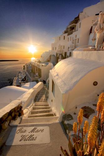 a sunset on the side of a building with stairs at Oia Mare Villas in Oia