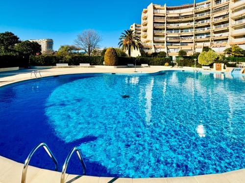 une grande piscine bleue devant un immeuble dans l'établissement Somptueux 3 pièces vue sur piscine, à Mandelieu-la-Napoule