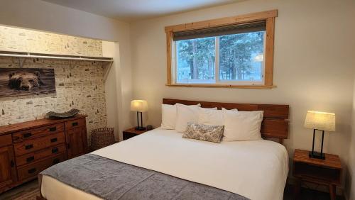 a bedroom with a white bed and a window at Beargrass Lodging & RV Resort in Hungry Horse